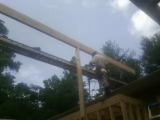 Carpenter setting a ridge beam over a new addition frame — Ice Dam Removal by Roofing Brothers in Capac
