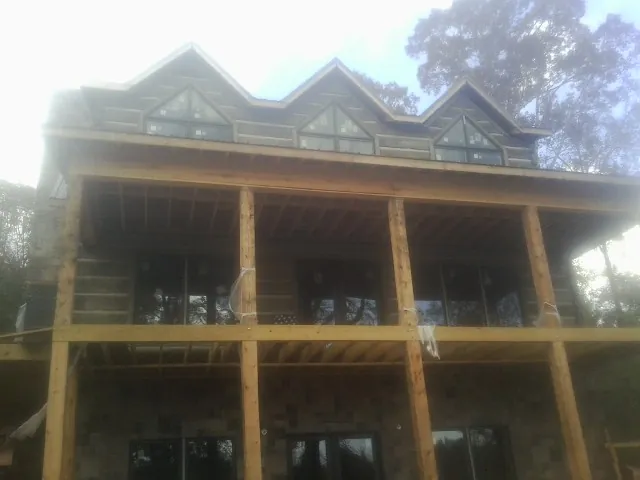 Dormers and porch framing on a large log home under construction — Roof Coating work by our crew in Capac