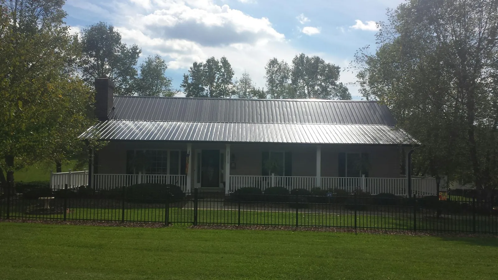 Gray metal roof on a brick ranch with a full width front porch — Gutter Guard Installation work by our crew in Capac